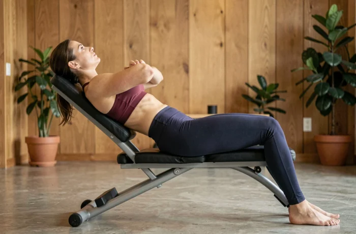 Femme réalisant une extension dorsale sur chaise romaine dans un studio de fitness moderne